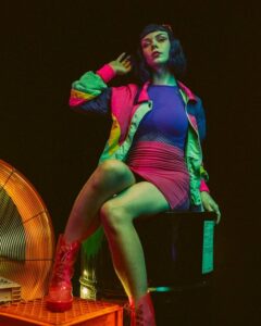 Woman in colorful hipster clothes posing in dark