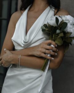 A woman wearing a white satin gown with flowers in her hands